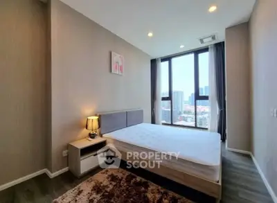 Spacious bedroom with large window offering city views, modern decor, and cozy ambiance.