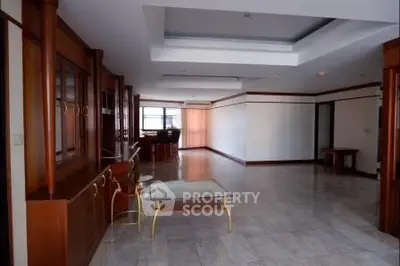 Spacious living room with elegant wooden accents and modern glass coffee table.