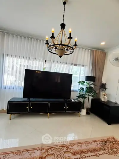 Elegant living room with chandelier, large TV, and stylish decor