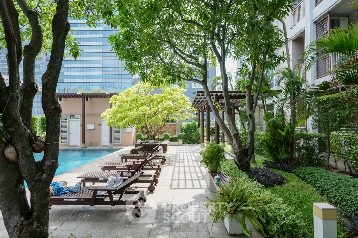 Luxurious poolside area with lush greenery and sun loungers in a modern residential complex.