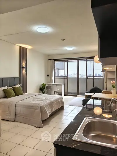 Modern studio apartment with open layout, featuring a cozy bed, kitchenette, and city view balcony.