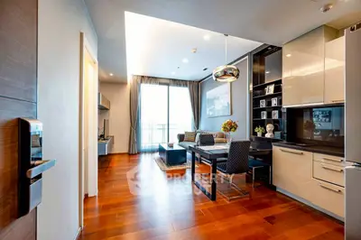 Modern open-plan living room with sleek kitchen and dining area, featuring hardwood floors and stylish decor.