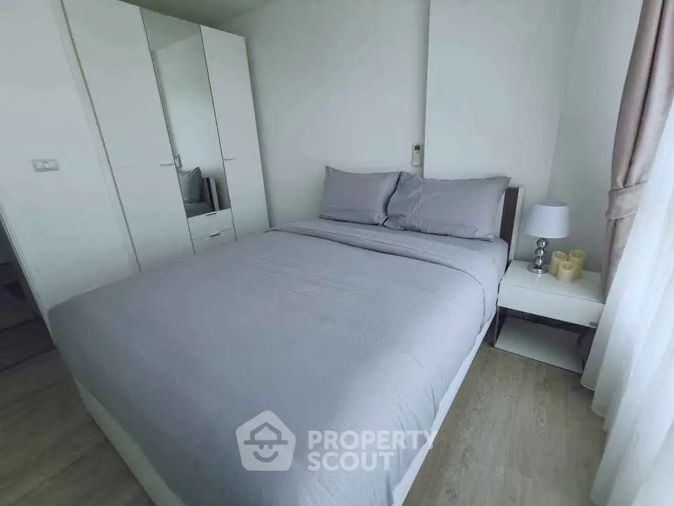 Cozy modern bedroom with stylish gray bedding and ample natural light.