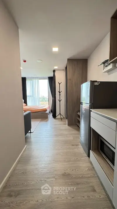 Modern studio apartment with open layout and sleek kitchen appliances.
