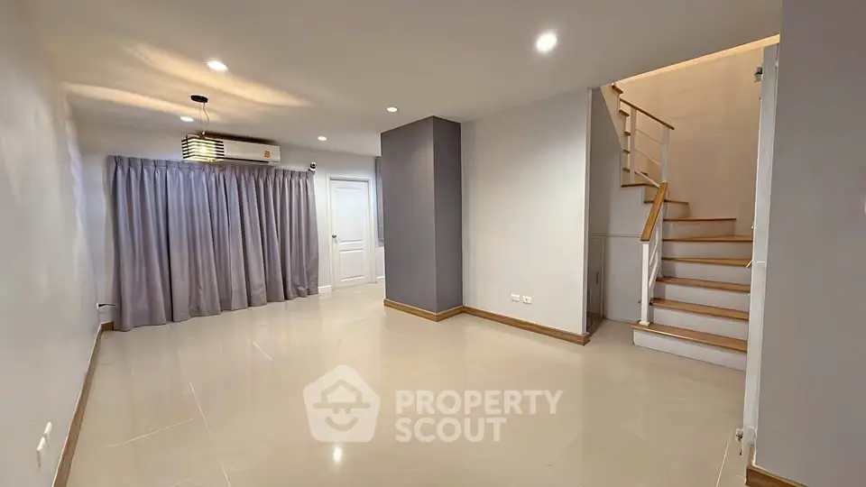 Spacious modern living room with elegant staircase and ample natural light.