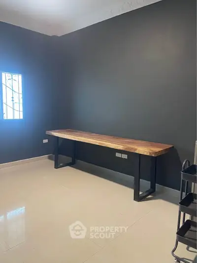 Spacious study room with elegant wooden desk and modern dark walls.