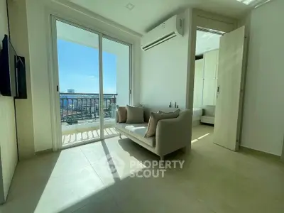 Bright living room with balcony and ocean view, featuring modern sofa and air conditioning.