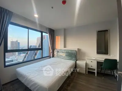 Modern bedroom with city view, featuring a large window and stylish furnishings.