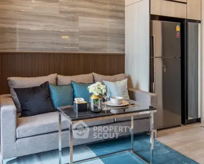 Modern living room with sleek sofa and stylish decor, featuring a stainless steel fridge and elegant table setting.