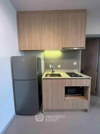 Modern compact kitchen with sleek wooden cabinets and stainless steel appliances.
