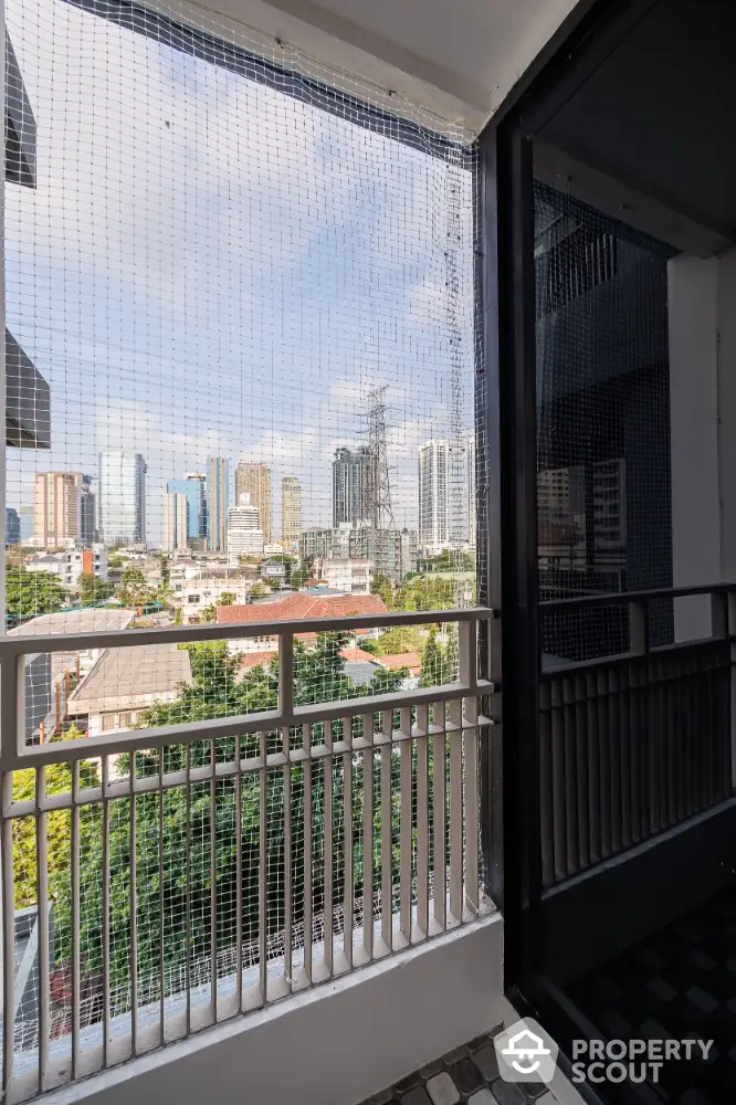 Stunning city view from a modern balcony with safety netting and railing.