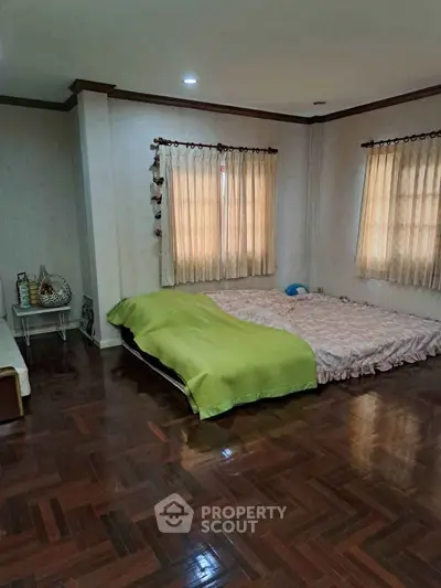 Spacious bedroom with wooden flooring and cozy decor