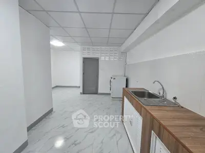 Spacious kitchen with modern sink and washing machine in sleek white interior.