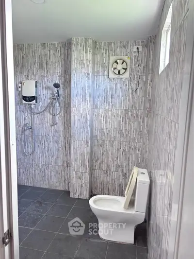 Modern bathroom with sleek gray tiles and essential fixtures, offering a clean and functional design.