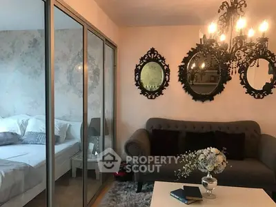 Elegant living room with chandelier and mirrored decor, adjacent to cozy bedroom.