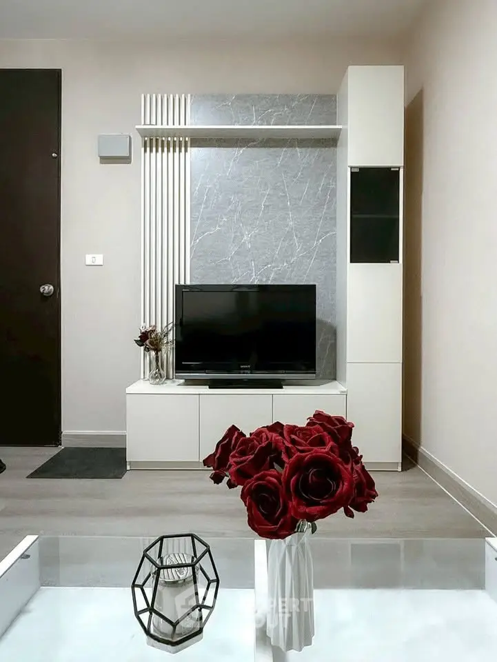 Modern living room with stylish decor and flat-screen TV, featuring elegant red roses.