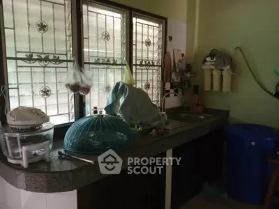 Cozy kitchen with natural light and ample counter space, featuring a closed layout and essential appliances.