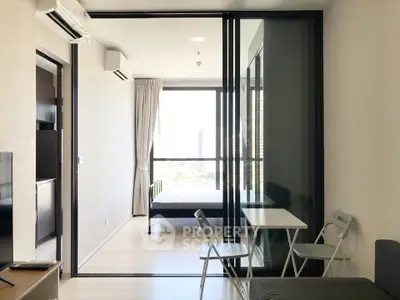 Modern apartment with sliding glass doors separating living room and bedroom, featuring minimalist furniture.