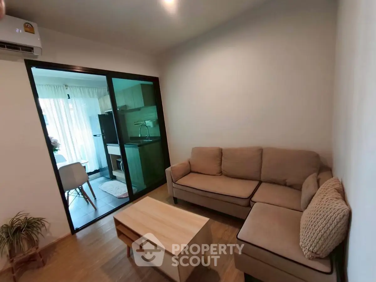 Cozy living room with modern furniture and sliding glass doors leading to a bright dining area.