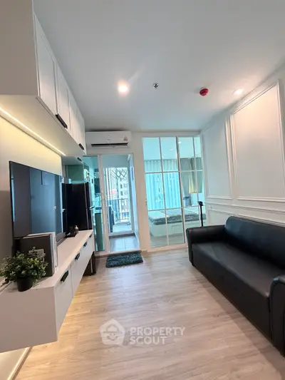 Modern living room with sleek design and glass partition leading to bedroom