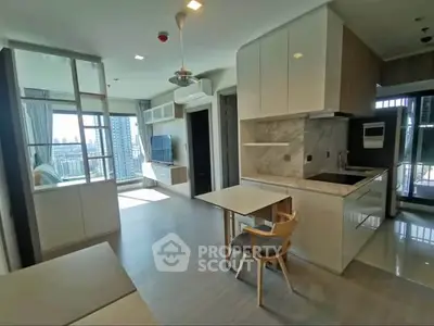 Modern open-layout living room with kitchen and balcony view in a high-rise apartment.