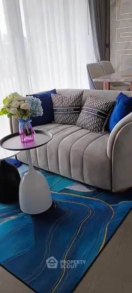 Stylish living room with modern sofa, vibrant blue rug, and elegant decor.