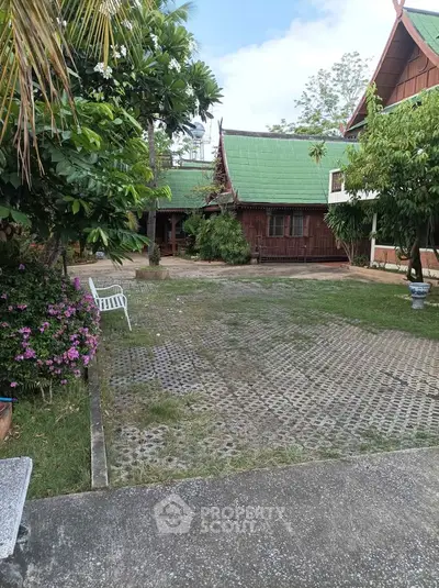 Charming traditional wooden house with lush garden and green roof, perfect for serene living.