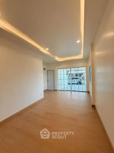 Spacious empty room with wooden flooring and recessed lighting