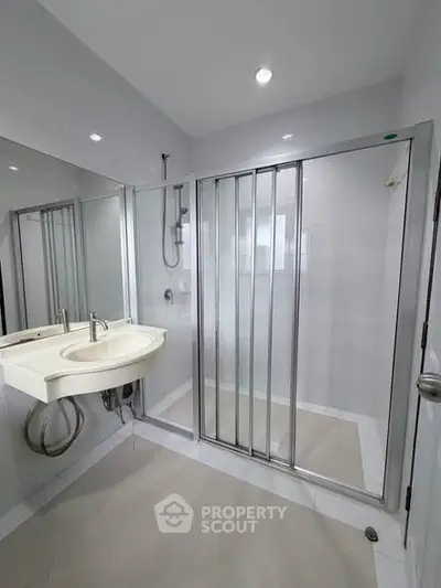 Modern bathroom with sleek shower enclosure and stylish sink in a contemporary home.