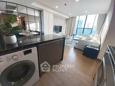 Modern open-plan living room with city view, featuring sleek kitchen and cozy seating area.