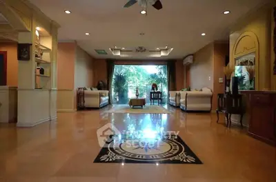 Spacious living room with elegant decor and large windows offering lush garden views.