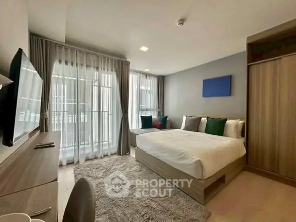 Modern bedroom with large windows and stylish decor, featuring a cozy bed and sleek furniture.