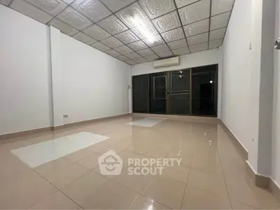 Spacious empty room with tiled floor and large windows, ideal for customization.