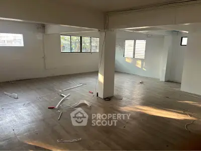 Spacious empty room with large windows and wooden flooring, ideal for customization.