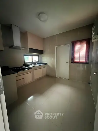 Modern kitchen with sleek cabinets and gas stove, featuring natural light through window blinds.