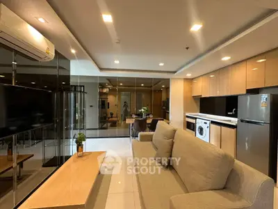 Modern living room with open kitchen, featuring sleek appliances and stylish decor.