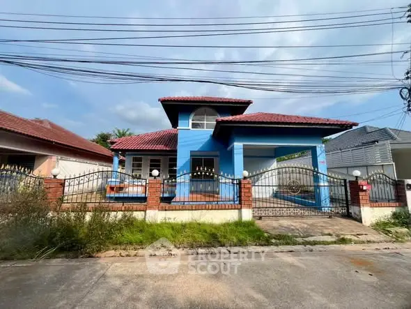 Charming blue house with red roof and gated entrance in a suburban neighborhood.