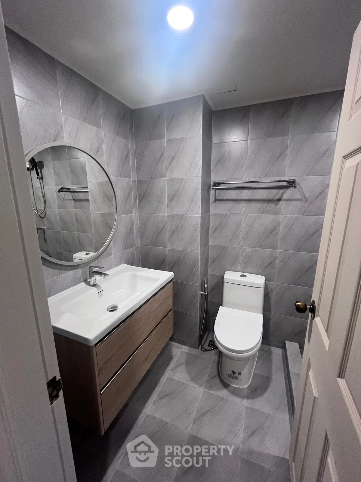 Modern bathroom with sleek gray tiles and round mirror