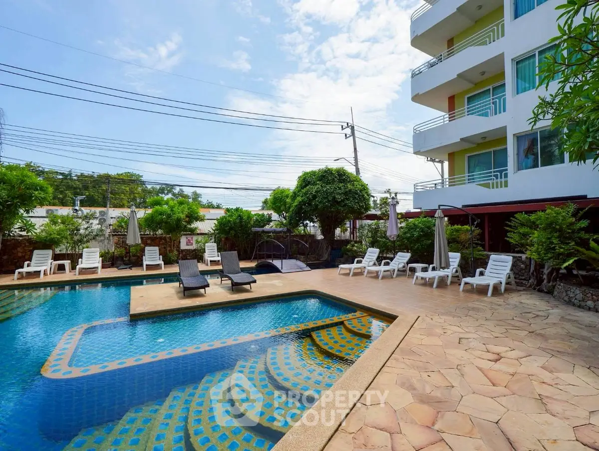 Luxurious apartment complex with inviting outdoor pool and sun loungers, perfect for relaxation.