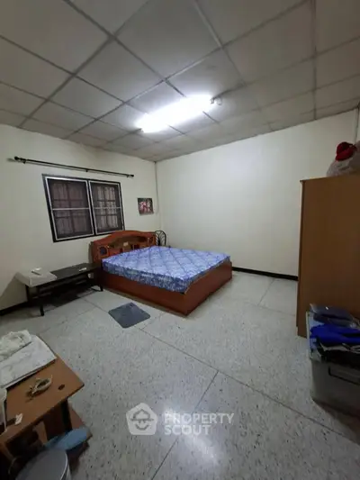 Spacious bedroom with simple furnishings and tiled flooring, ideal for comfortable living.