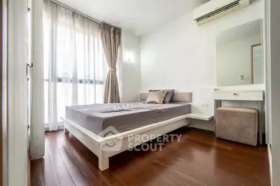 Modern bedroom with wooden flooring, large window, and minimalist decor.