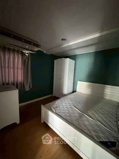 Cozy bedroom with white furniture and teal walls, featuring a bed and wardrobe.