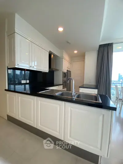 Modern kitchen with sleek black countertops and white cabinetry in a bright apartment.