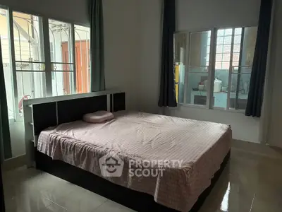 Cozy bedroom with large windows and simple decor, perfect for relaxation.