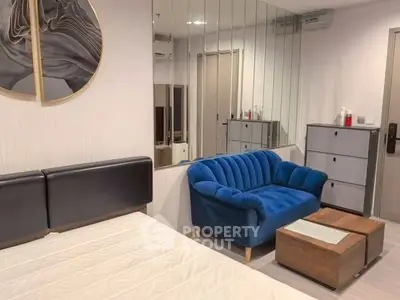 Modern bedroom with stylish blue sofa and mirrored wall decor