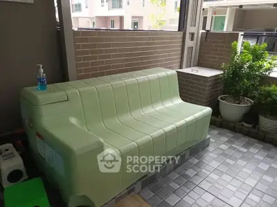 Spacious balcony with green storage bench and potted plants, perfect for relaxation.