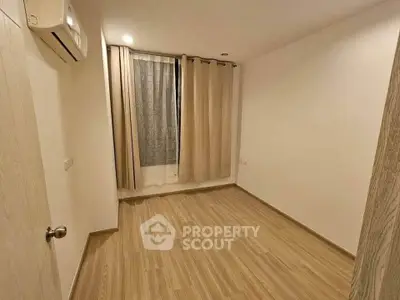 Spacious empty bedroom with wooden flooring and air conditioning, ready for customization.