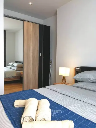 Modern bedroom with stylish decor and cozy ambiance, featuring a neatly made bed and elegant lighting.