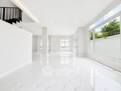 Spacious modern living room with large windows and glossy white flooring