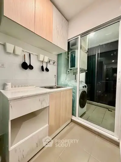 Modern kitchen with sleek cabinetry and washing machine in compact space.